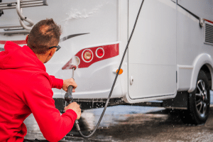 Man washing tail lights of his RV.