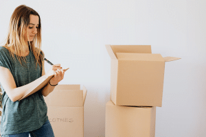 Woman taking notes about contents of her boxes for storage unit cleanout.