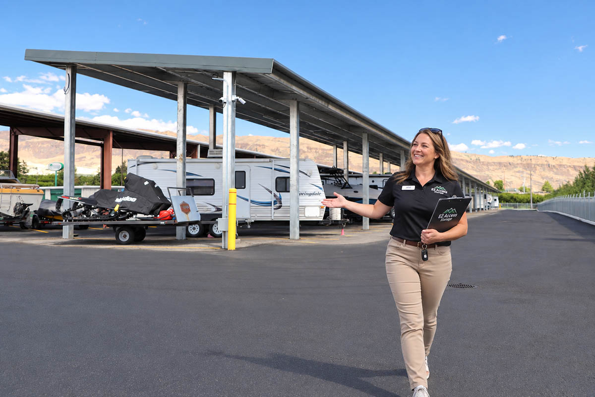 Tour-EZ-Access-Storage EZ Access Storage team member giving a facility tour beside covered snowmobile and RV storage near Wenatchee, WA